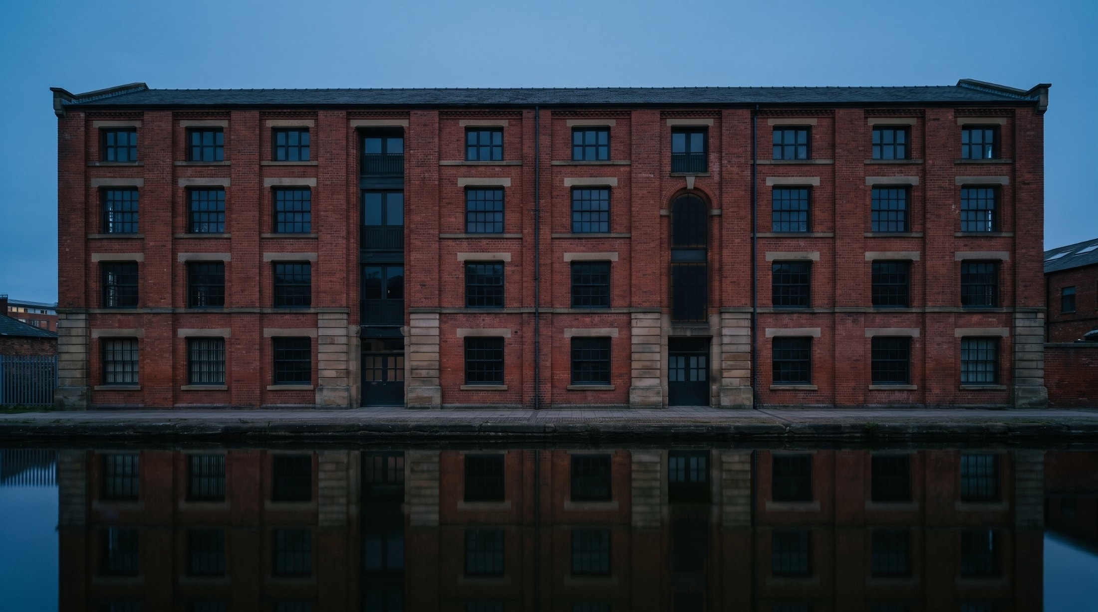 North Quay Works at dusk, a four-storey brick warehouse on a canal, its windows dark.